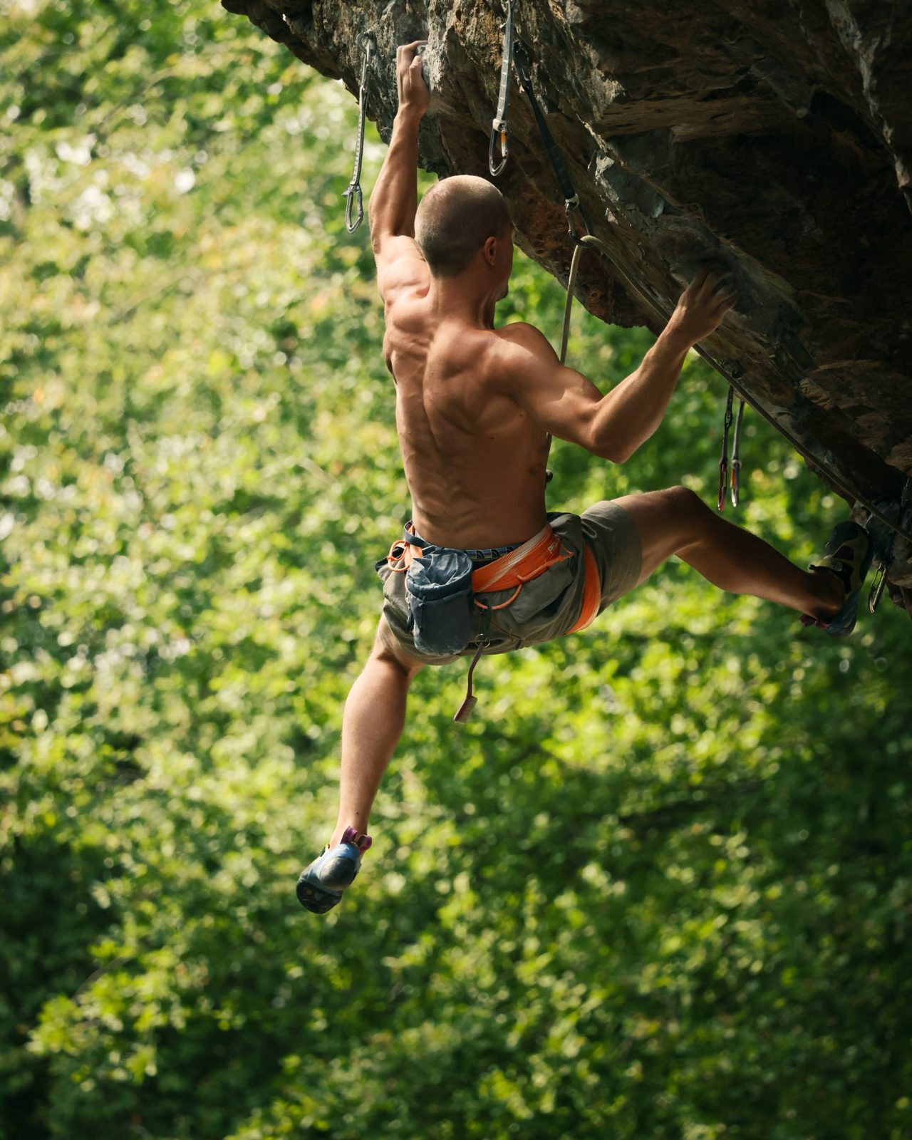 Climber on an overhang against green trees