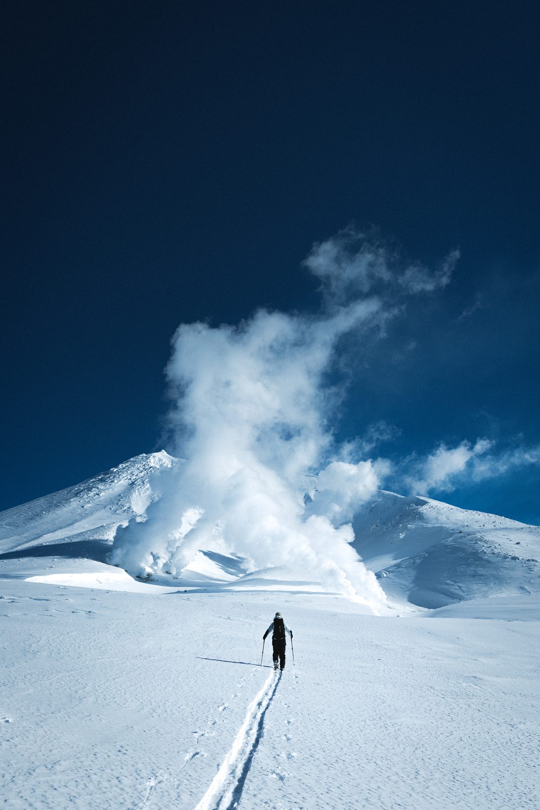 Ski tourer below a steaming volcano