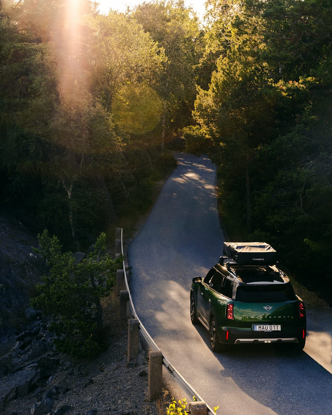Car with a roof tent on a forest road at sunset