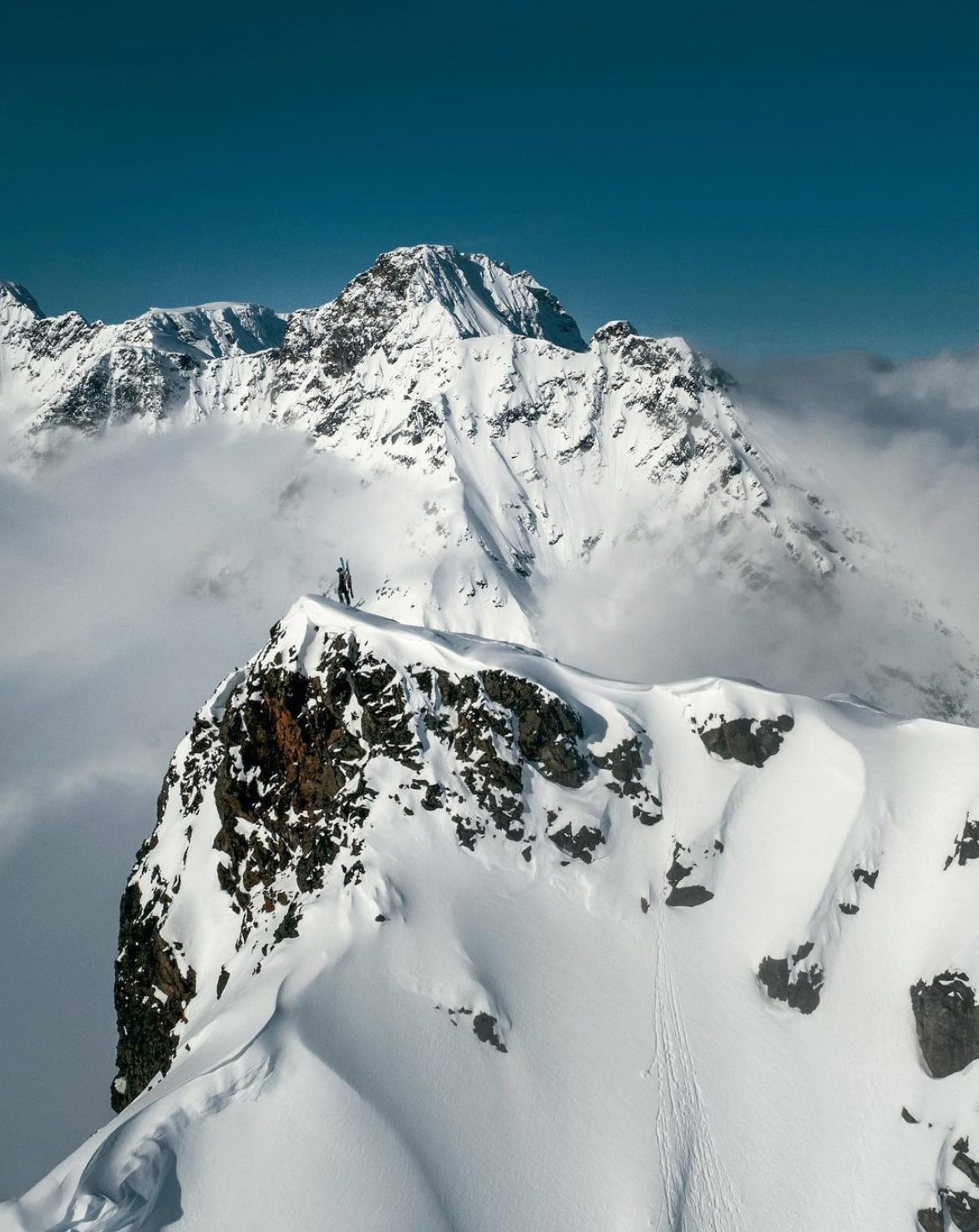 Skier on a snowy summit ridge