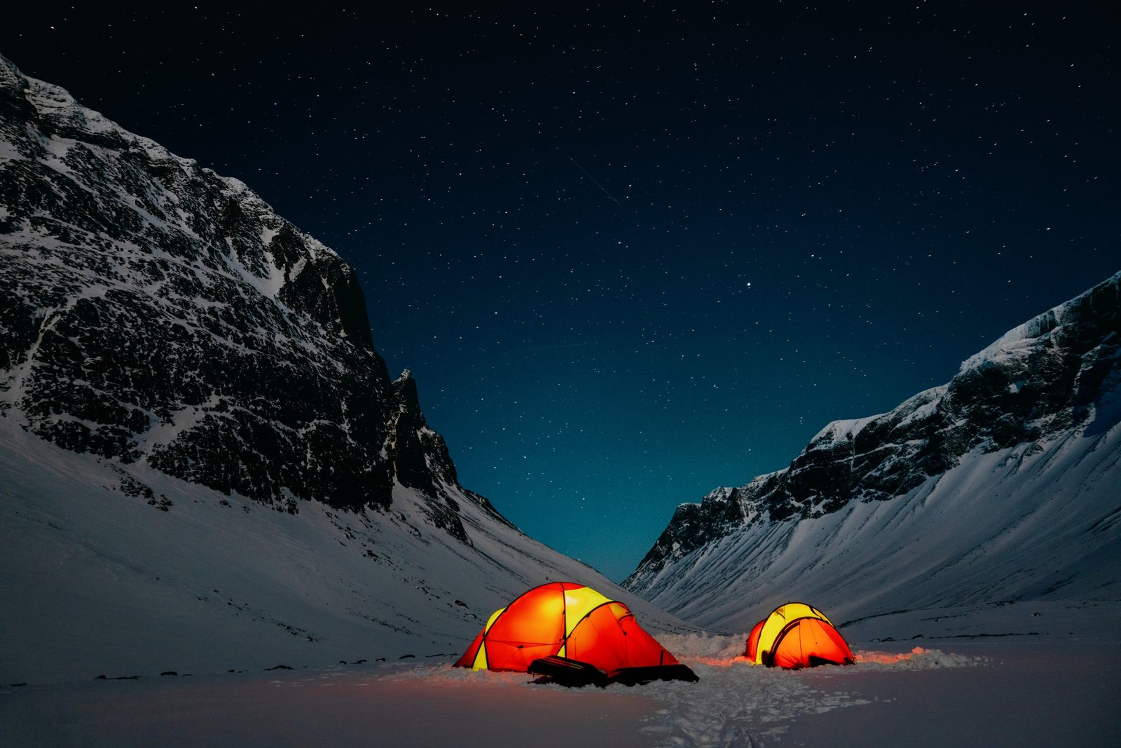 Lit tents under the stars in a mountain valley
